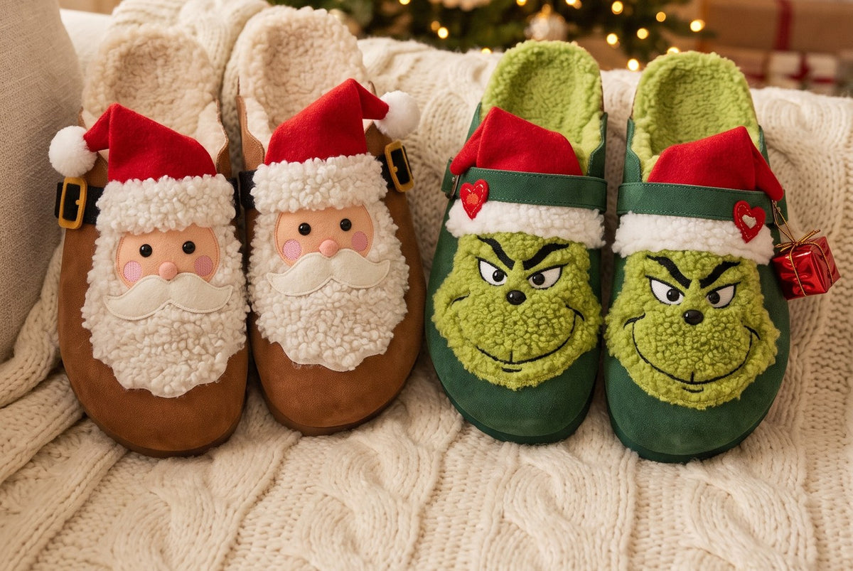 The Santa Clog in brown suede and the Green Meanie Clog in green suede, side by side on a cream knit blanket in front of a Christmas tree